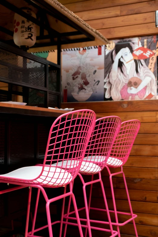 three bright pink chairs in front of wood paneled walls