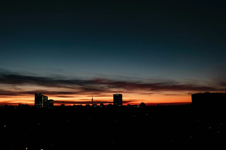 the setting sun reflects off a silhouette of skyscrs