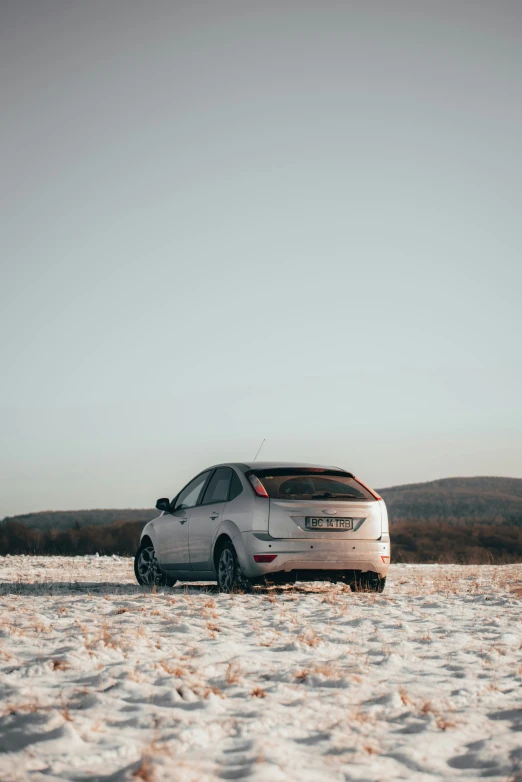 a small white car is parked on a snowy road