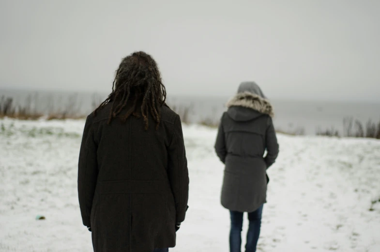 two people walking in the snow towards a large lake