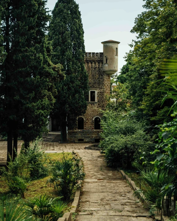 a stone building surrounded by trees and plants