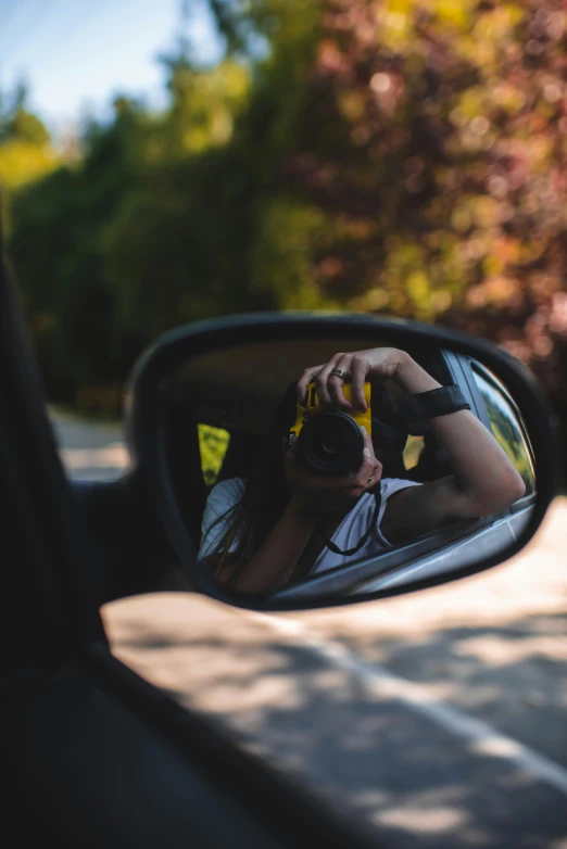 a young man takes his own pograph in the side mirror