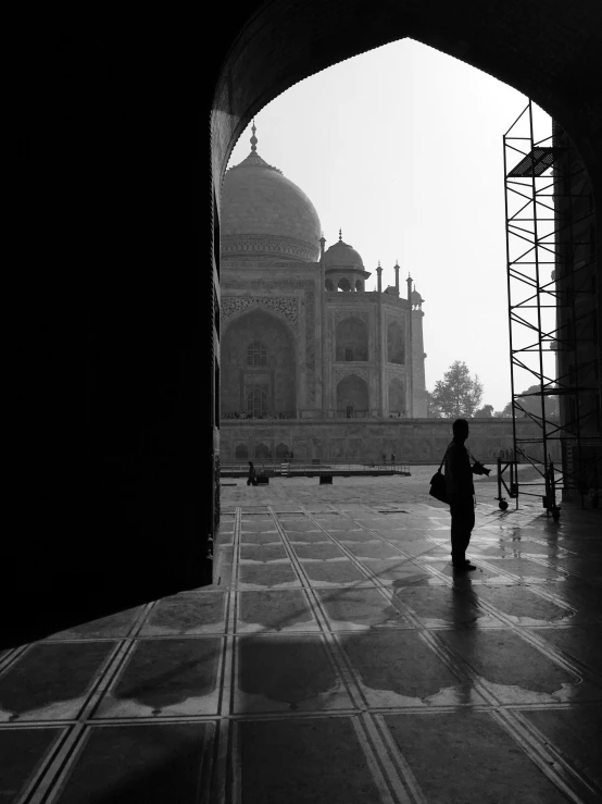 a black and white image with a person standing in front of the temple