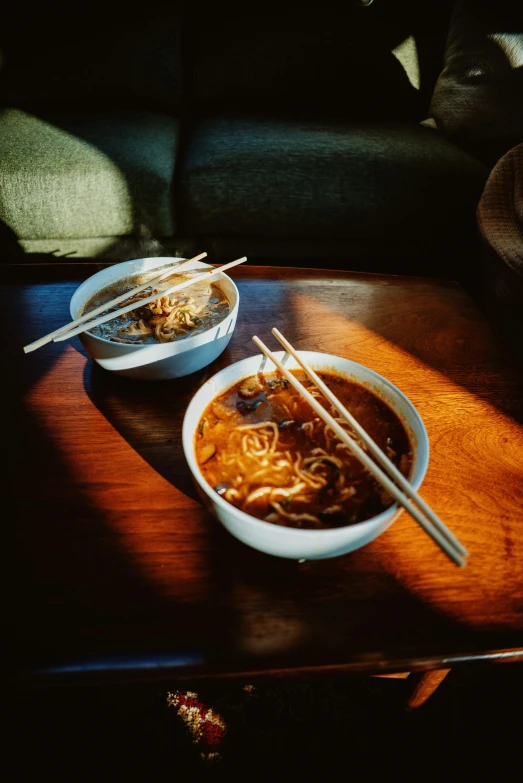 a bowl of noodle soup and two chopsticks sitting on a coffee table