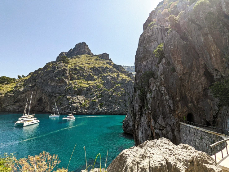 several boats are sailing in the water near mountains