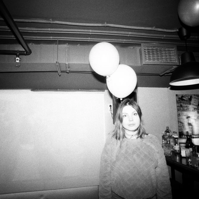 a woman in black and white holding balloons in a room