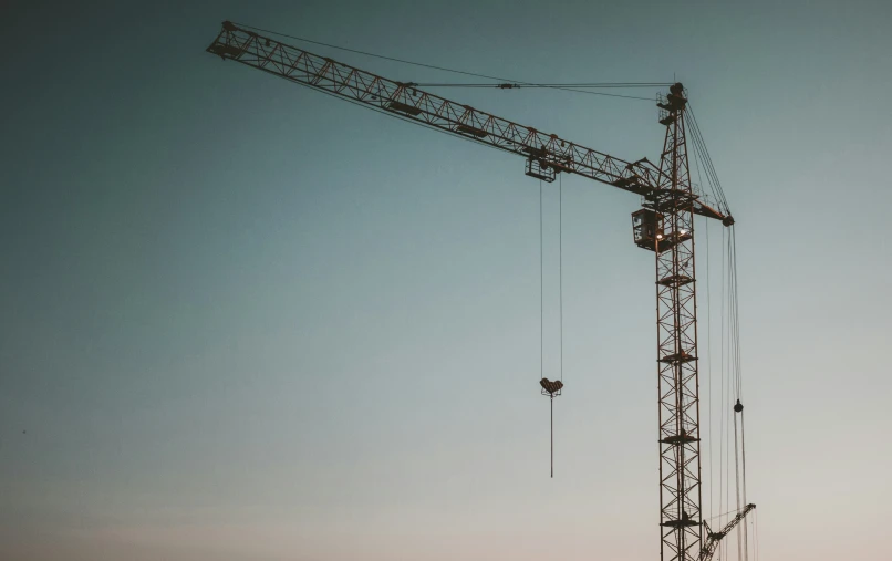 large tower cranes against a blue sky at dusk