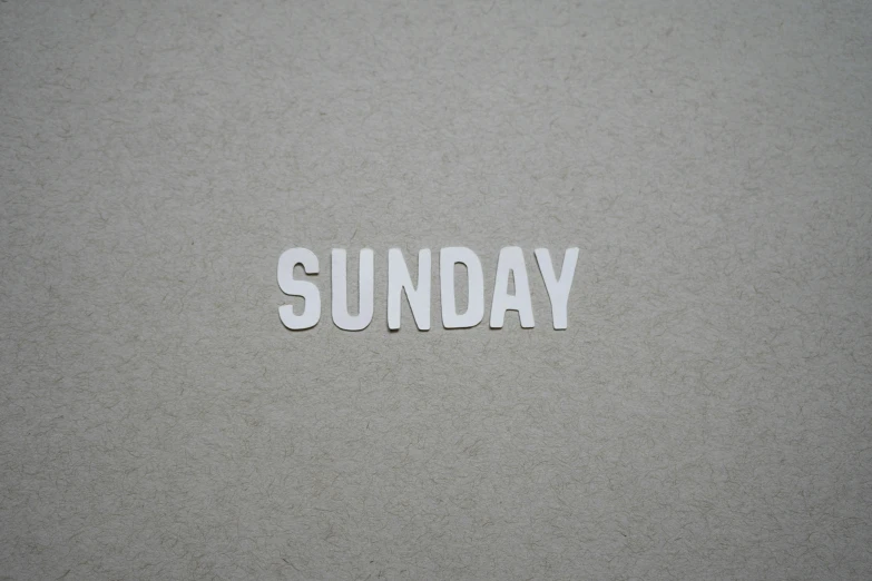 the word sunday spelled in small letters on sand