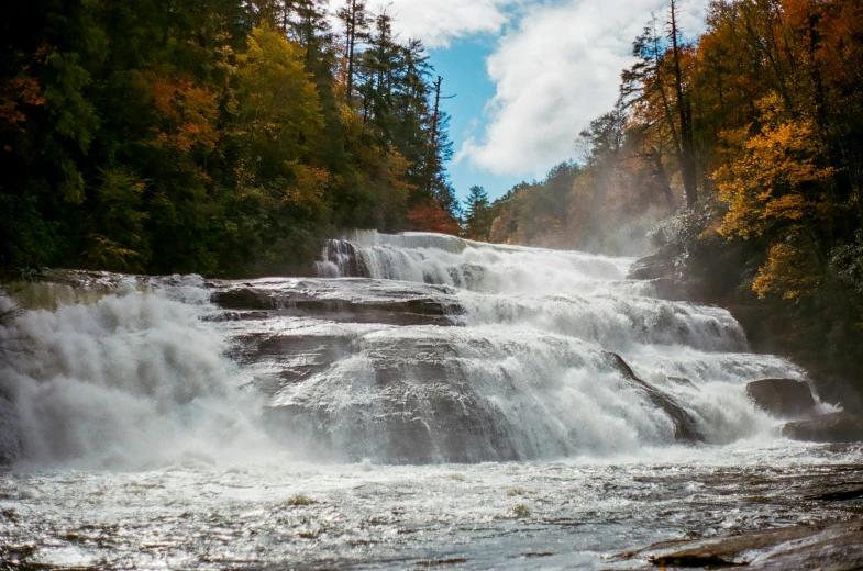 waterfall cascading up a river with a forest in the background