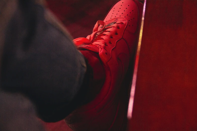 a red tennis shoe is sitting on a rail