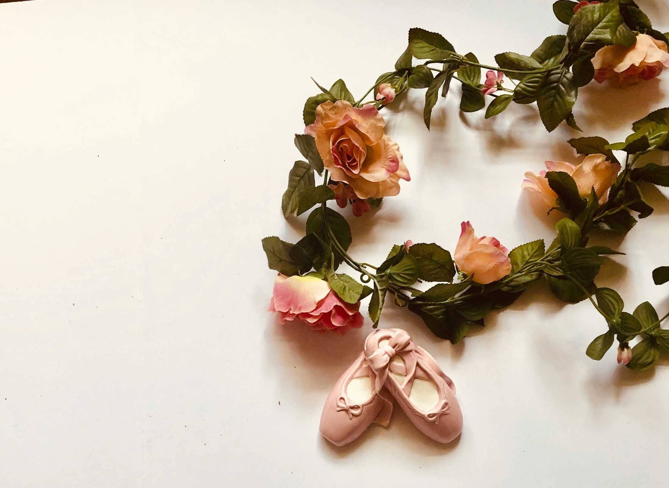 several ballet shoes on a nch of pink roses