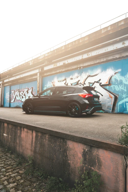 a black car parked in front of graffiti covered building