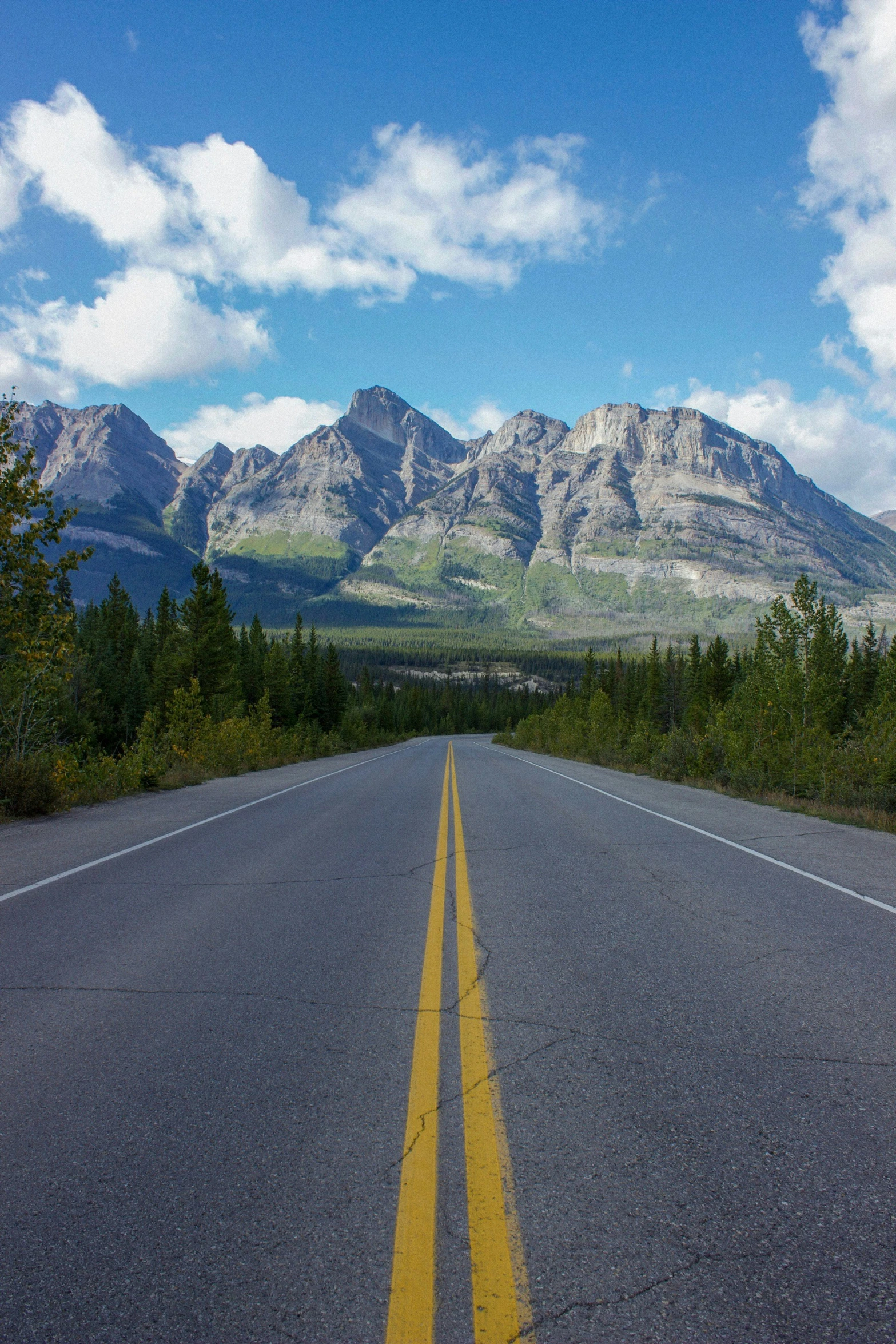 an empty roadway with mountains and sky in the background