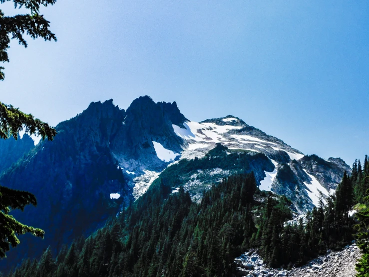 a rocky mountain with trees and a snow covered peak