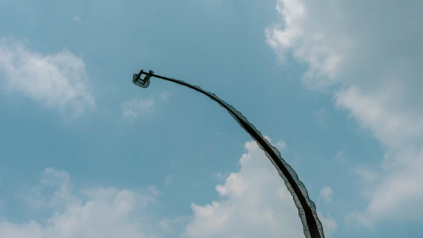 a streetlight on an ornate curved pole against a cloudy blue sky