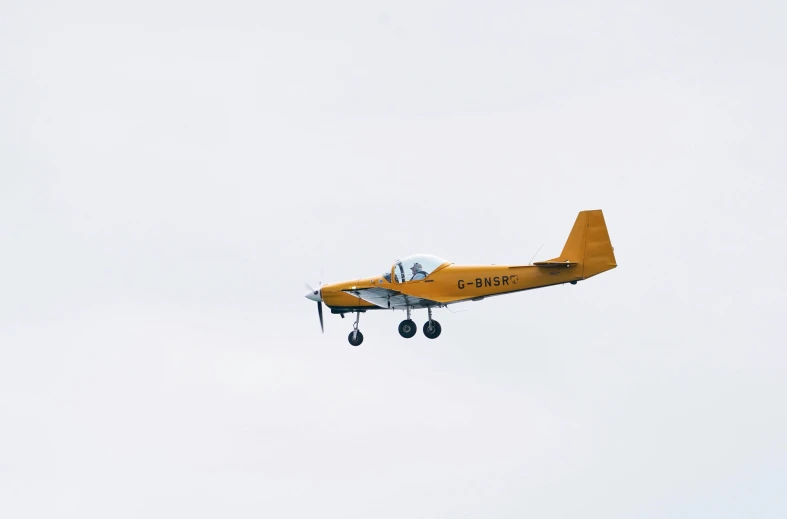 a yellow plane is flying through the sky