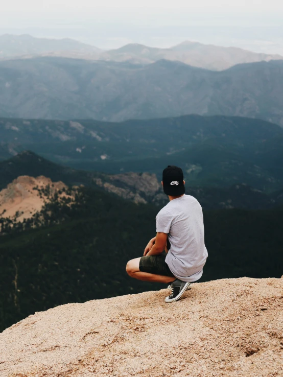 a man sitting on top of a mountain looking down