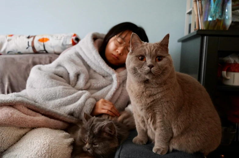 a woman is sitting next to two cats