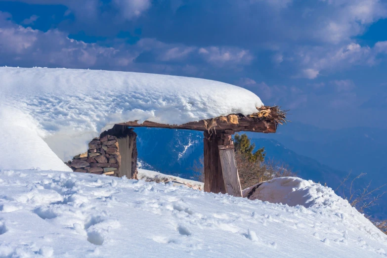 the snow covered area of a mountain with a large building structure that has it's roof torn down