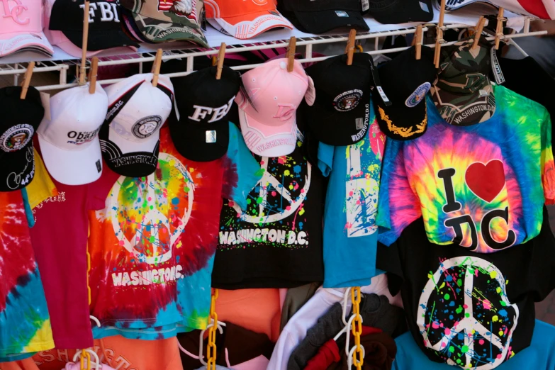 a variety of colorful hoodies and caps hanging from the wall