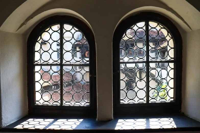 two arched windows with sunlight coming in and outside them