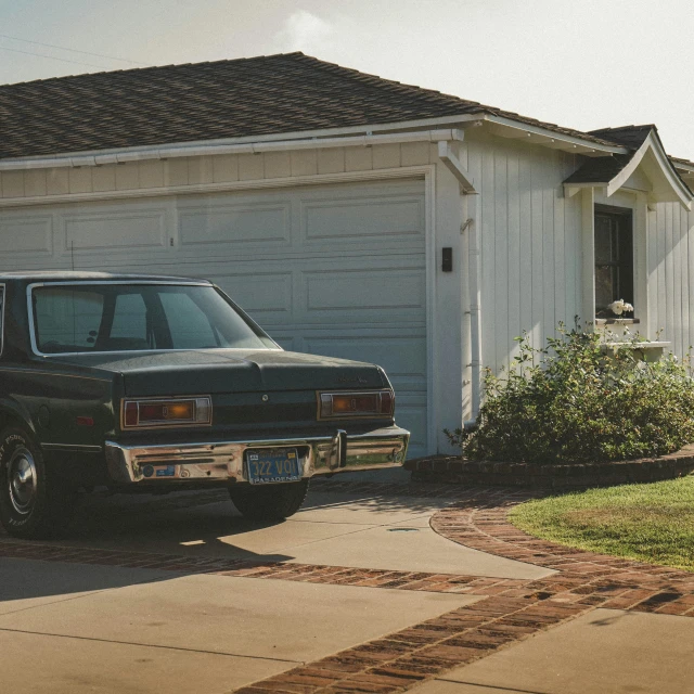 an old car parked in front of a white house