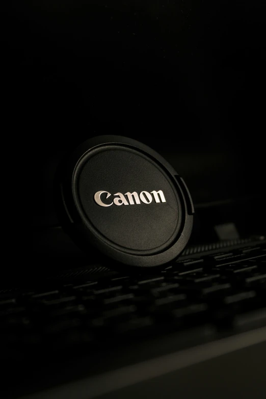 a close up view of a canon lens cap on a computer keyboard