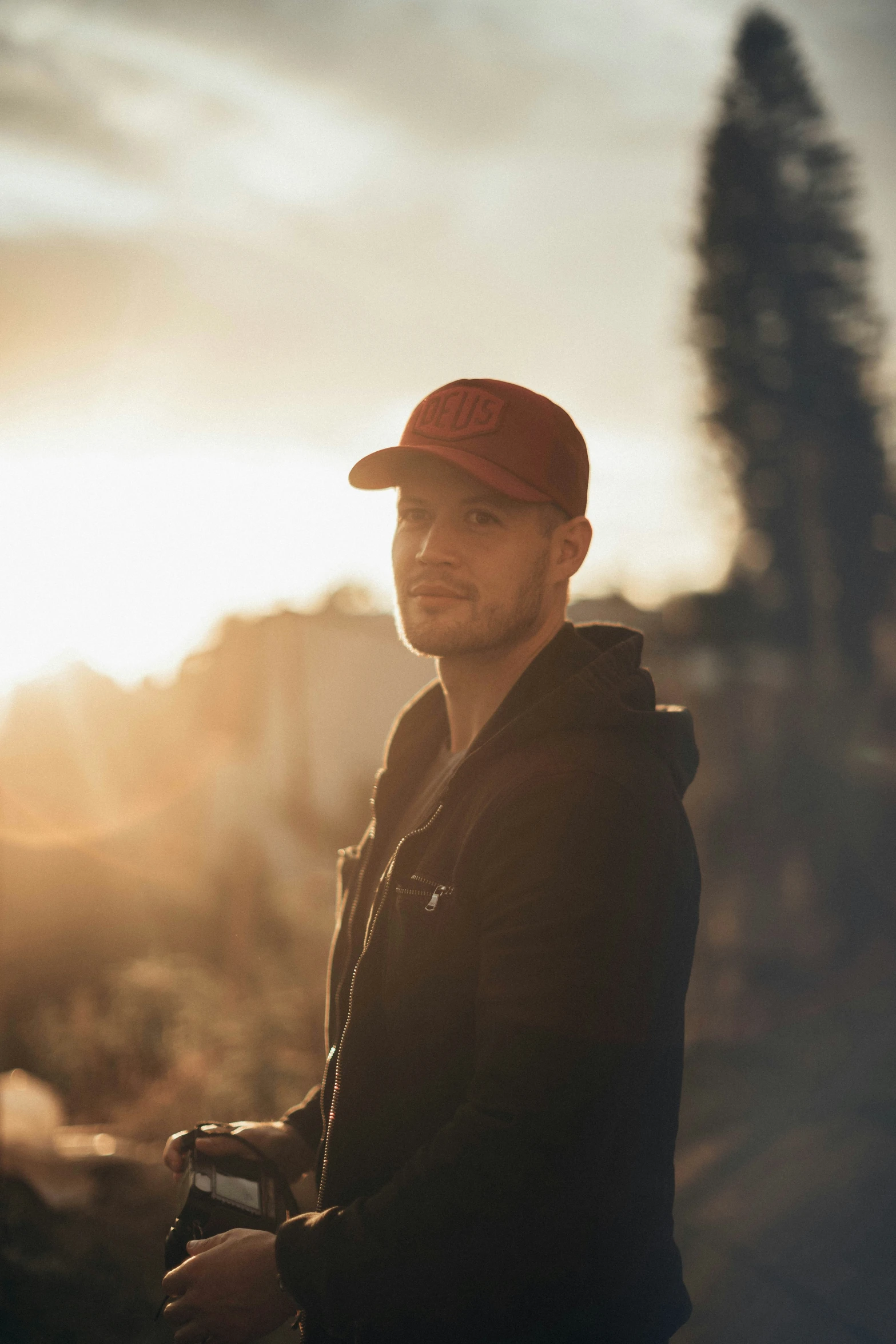 a man in a red hat holds his camera and poses for the camera