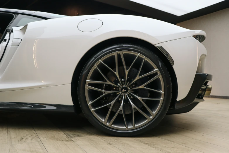 a white sports car with black rims sitting on the ground