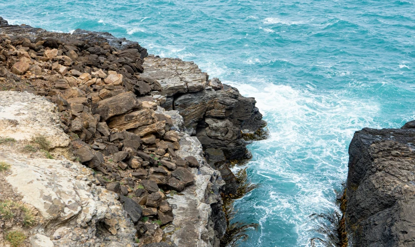 water is breaking over the edge of some rocks on a cliff