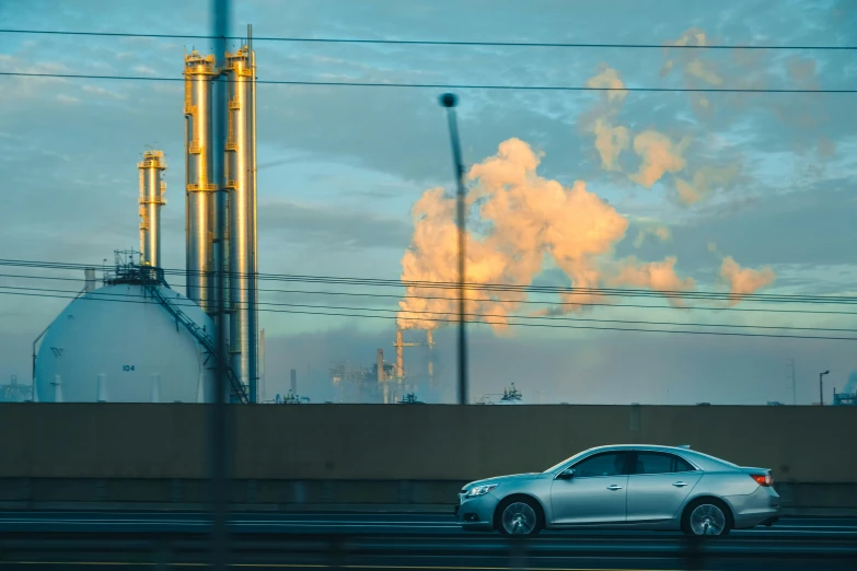 a car driving down the road past some factories