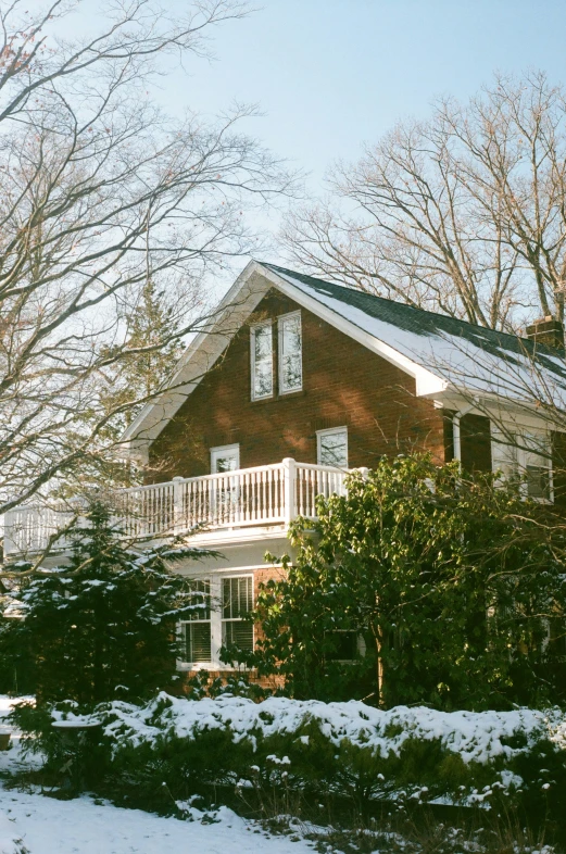 the back of a house with trees on the side and snow on the ground