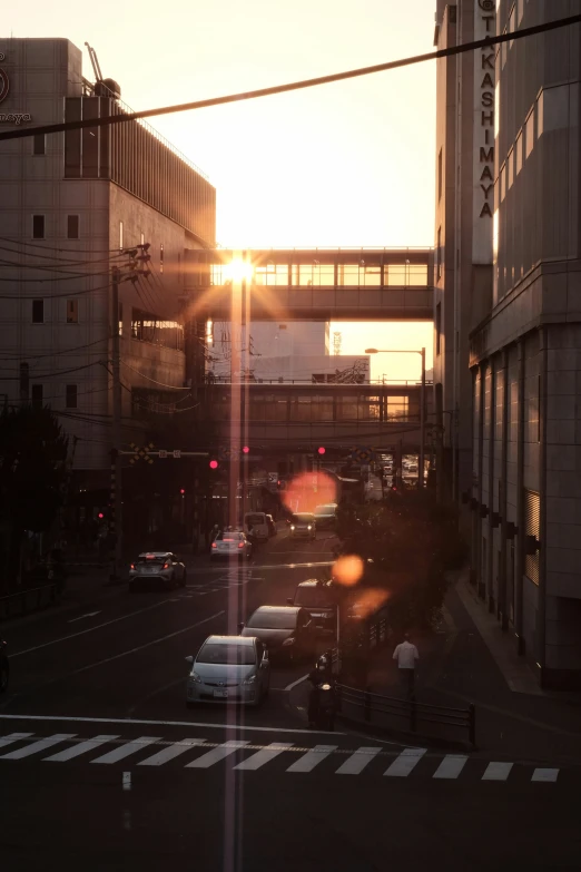 the sun sets on an urban street with traffic