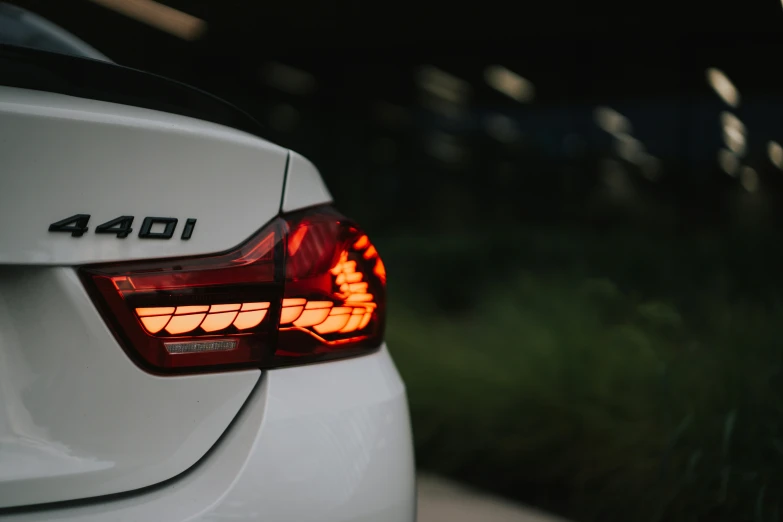 the tail light of a white car with a green lawn in the background