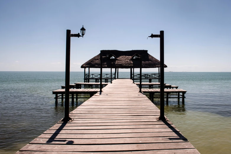 a dock with several benches and a roof in the water