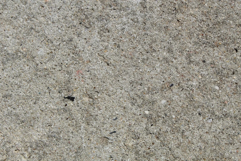 a sidewalk with small grey stains and dirt