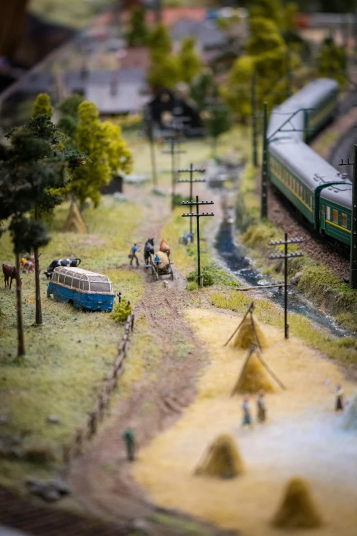 model of a train and other tracks with trees and people around