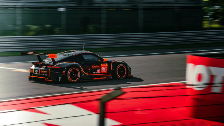 an orange and black car driving around a track