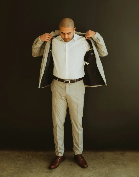 man in white dress shirt and brown shoes holding jacket open