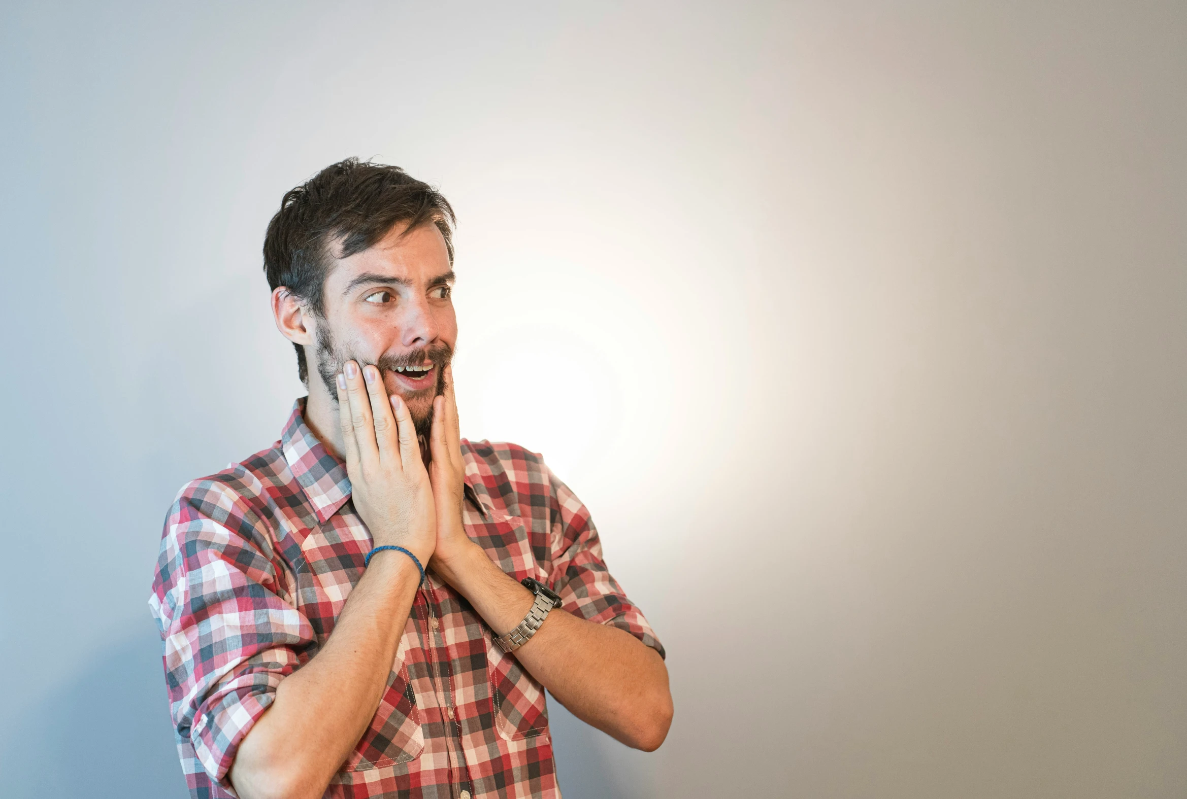 a man in plaid shirt with white hand under face