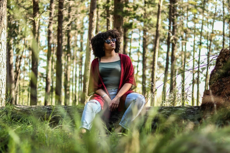 a woman in grey top sitting in the woods