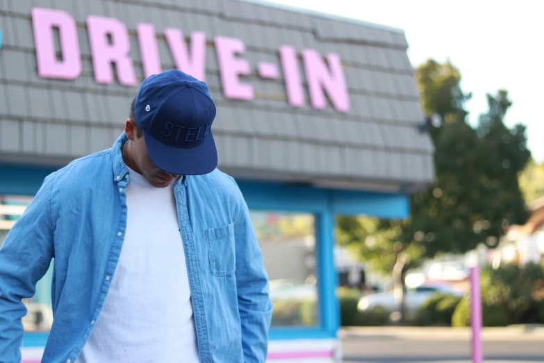 a man in a blue hat walks away from the drive - in