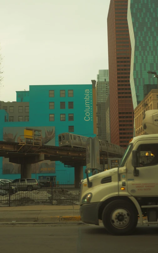 a truck drives near a large bridge and large buildings