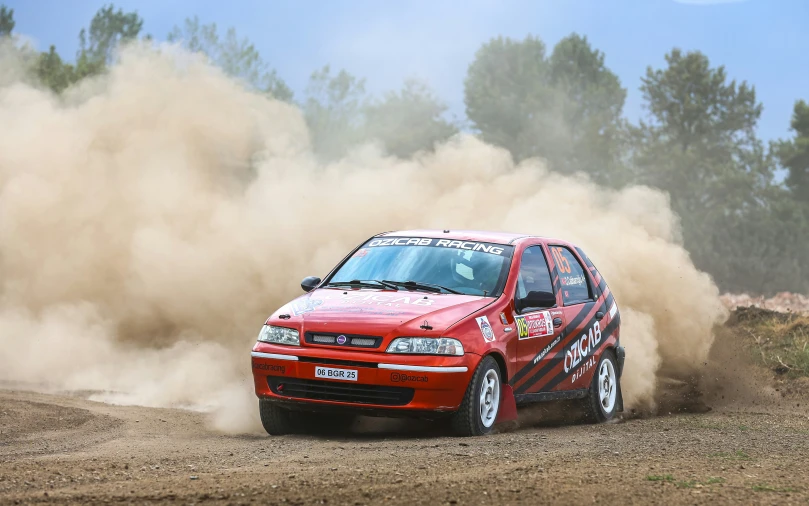 a small red car that is driving down a dirt road