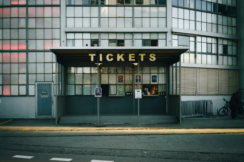 a couple of people walk outside of a ticket booth