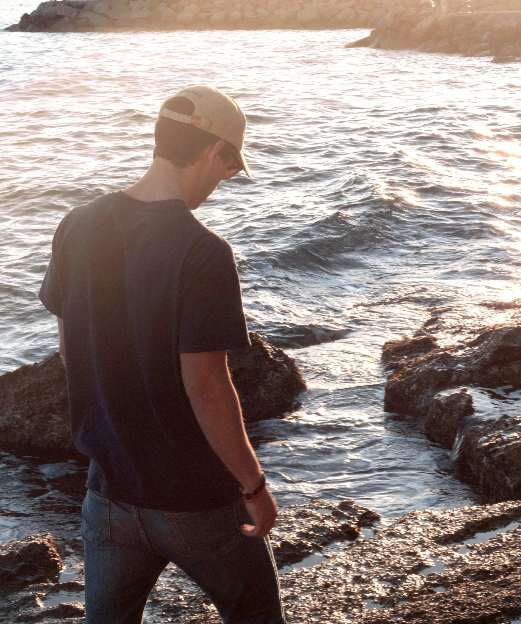 a man standing on the rocks overlooking a body of water