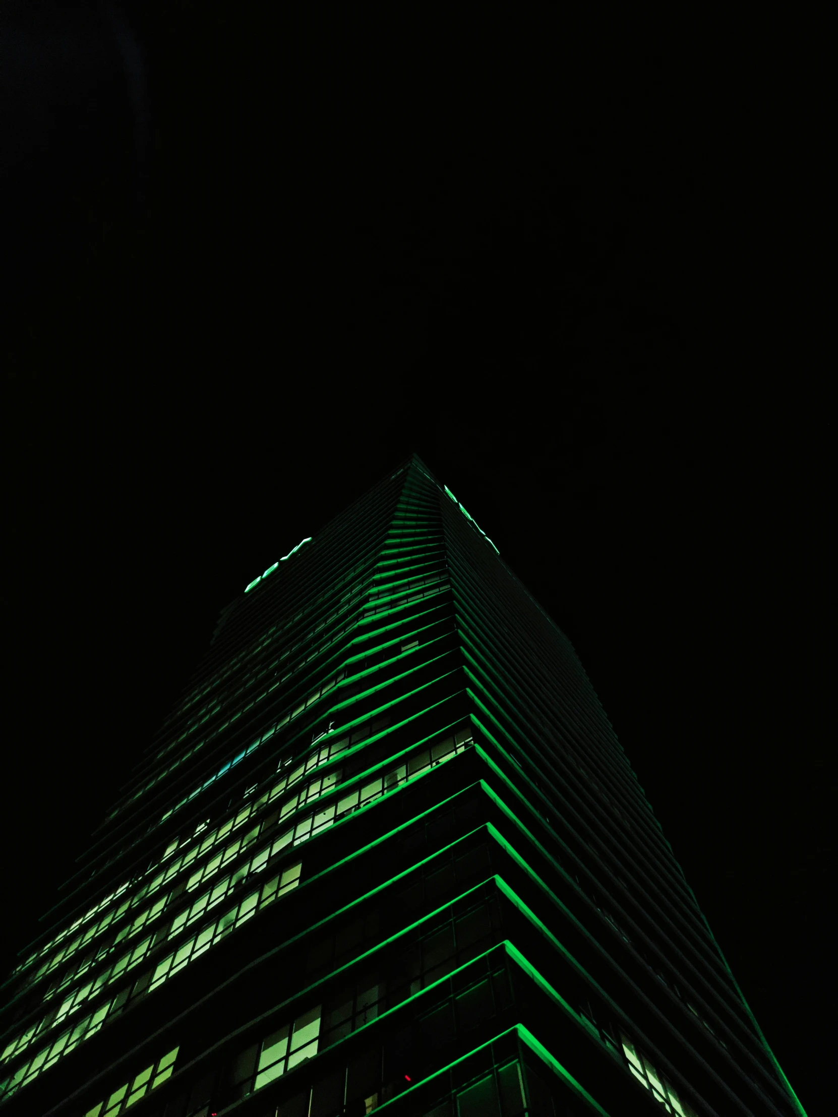 the top of a tall building lit up green in the dark
