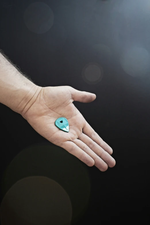 a person is holding out their hand with a small green stone