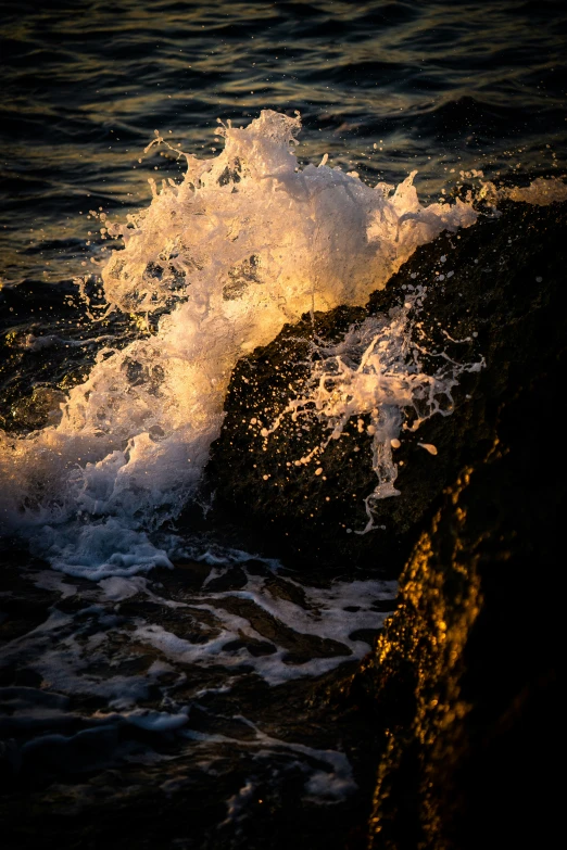 the water has spray on it while some rocks are close to shore