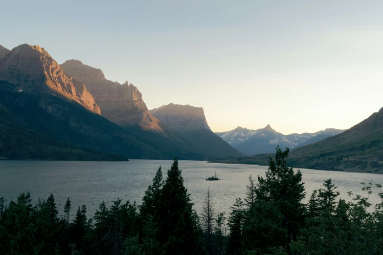 the sun shines brightly on the mountains surrounding a river